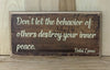 Don't let the behavior of others destroy your inner peace quote on wood sign.