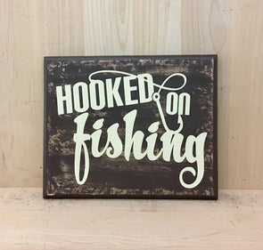 Hooked on fishing wood sign for cabin decor with fish hook design.